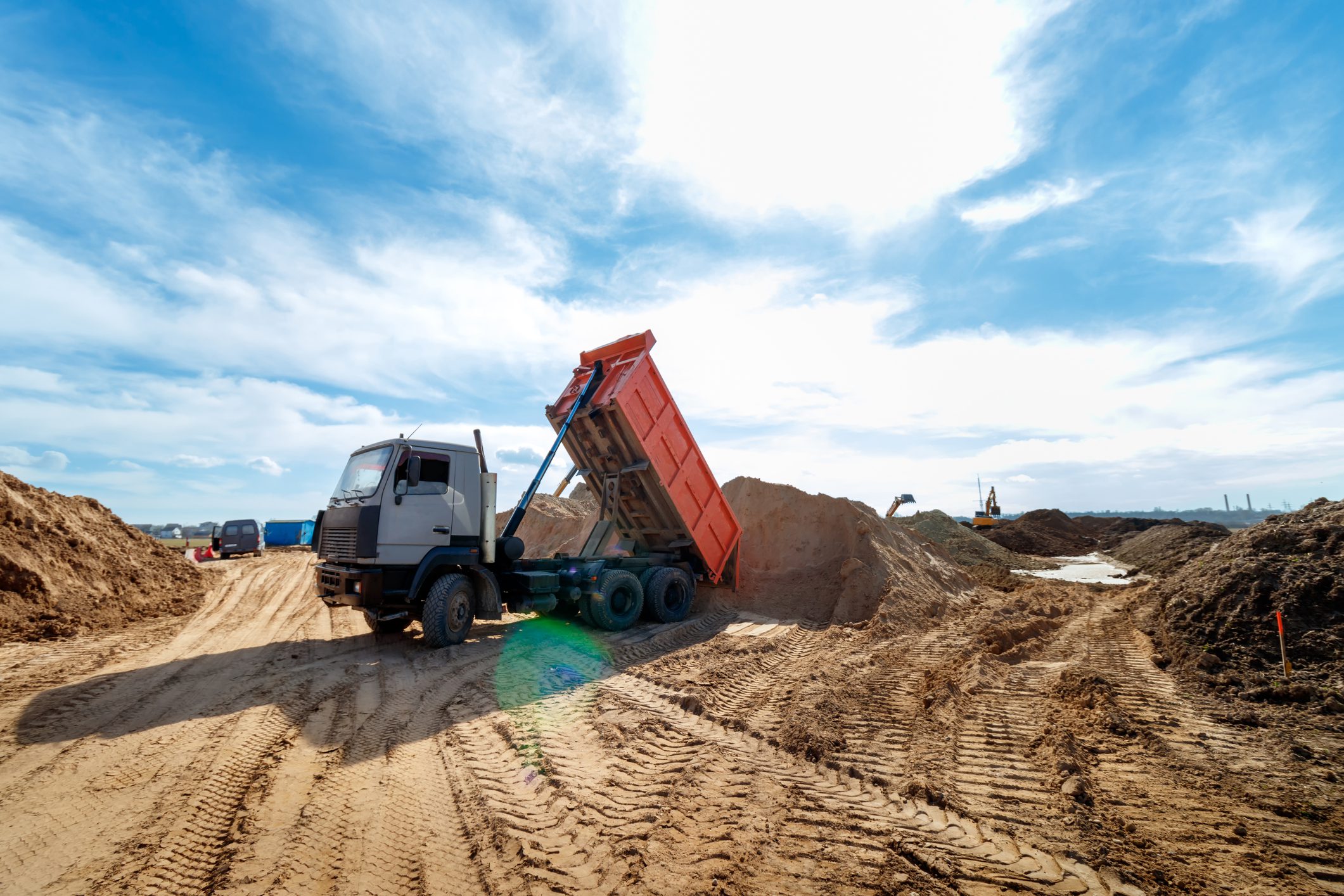 Dump truck unloading sand at construction site.