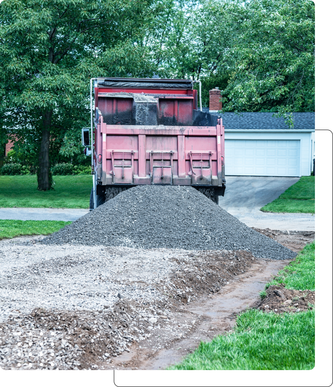 Dump truck unloading gravel onto driveway.